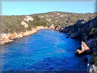 Bini Parratx es una cala con un codo y larga, lo que impide apreciarla desde si se visita en barco hasta que se entra al final tiene una playa pequeña, nudista